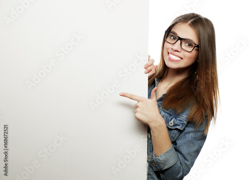 Gorgeous woman wearing glasses pointing at a board while standin