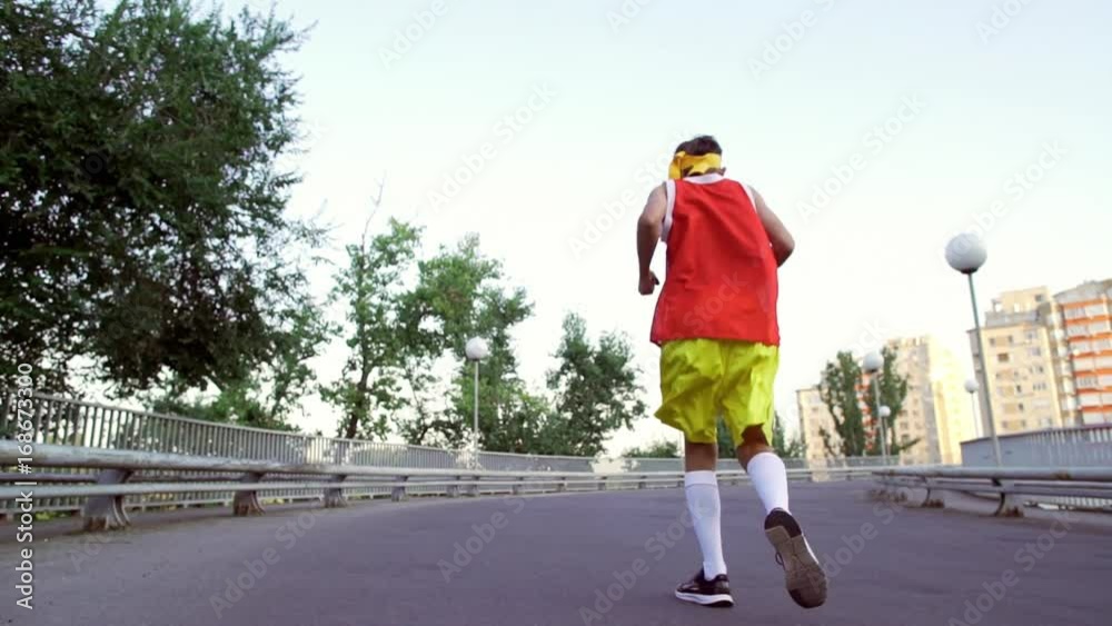 Funny thin guy in sports clothes jogging on the bridge in the morning. Funny thin guy in sports clothes jogging on the bridge in the morning.