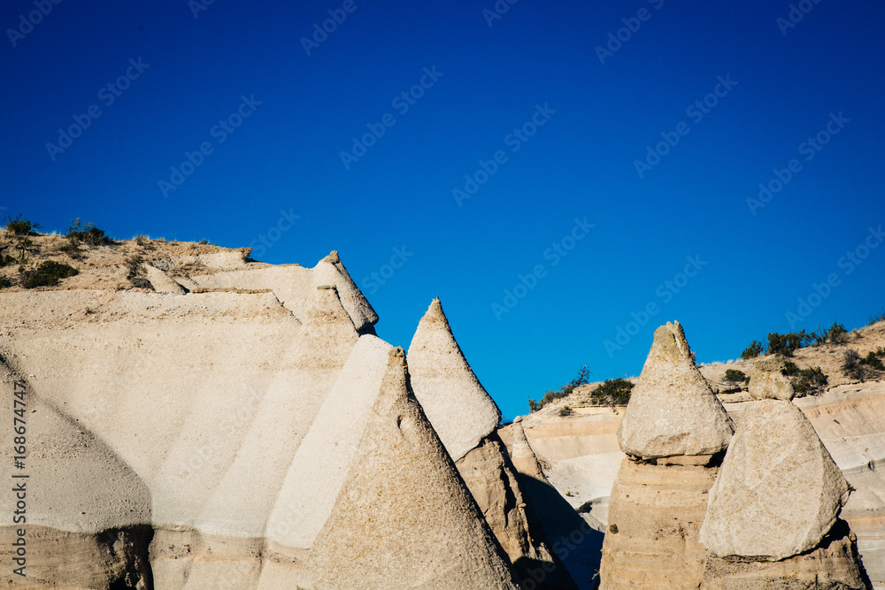 Cone shaped rocks form in the desert of New Mexico with a blue sky