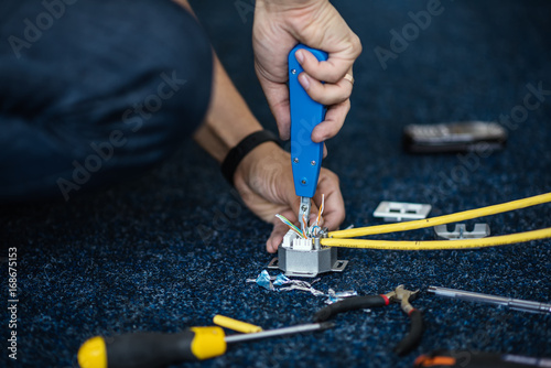 Worker connect a network cable with RJ45 sockets by punch-down tool, process of laying the local network. Set photo