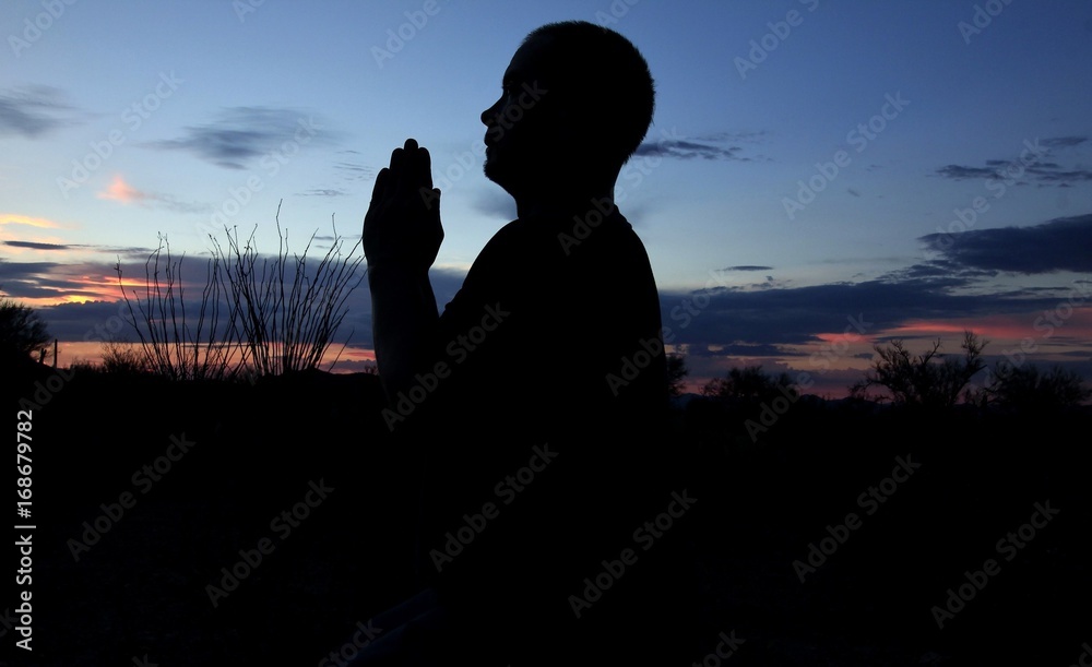 Silhouette of a man praying under a beautiful Arizona sunset. 