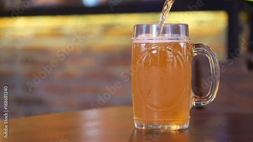 Pouring Beer In A Half Fulll Mug On A Brown Table  photo