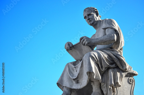 Statue of a man reading in Italy with blue sky