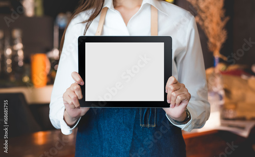 Close up on blank tablet computer that barista show and holding with two hand in front of coffee shop counter bar,Mock up space for display of menu or design