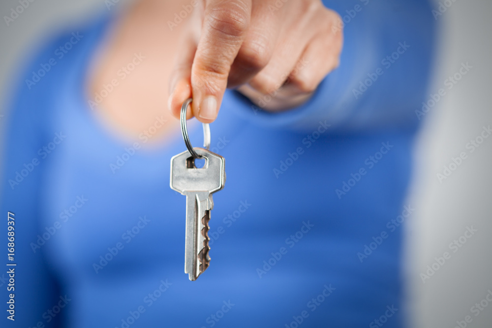 Woman holding home keys in front of her body. Focus on foreground Woman holding home keys in front of her body. Focus on foreground
