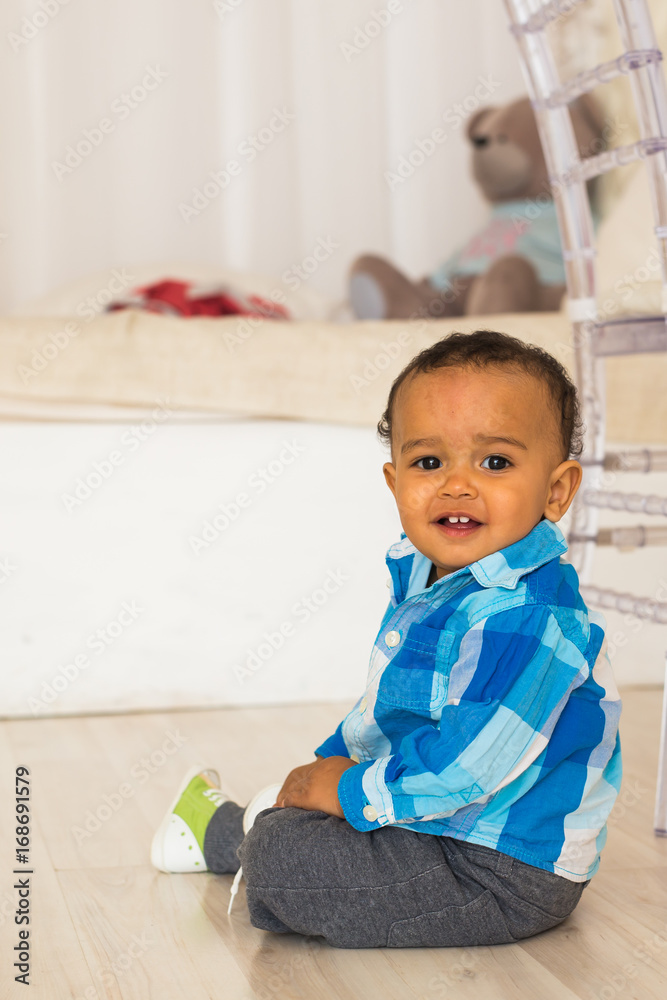 Full length portrait of a young mixed race boy sitting on the floor. Full length portrait of a young mixed race boy sitting on the floor.