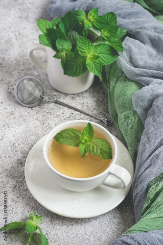 Natural mint tea and fresh mint leaves on a gray background