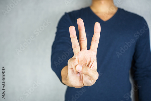 three finger salute hand gesture, on light grey background photo