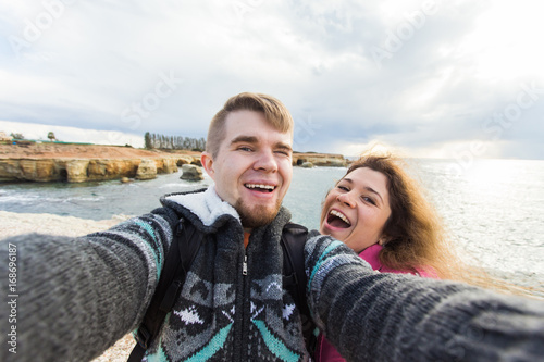 Happy young couple in love takes selfie portrait on the beach in Cyprus in autumn or winter. Pretty tourists make funny photos for travel blog in Europe. © satura_
