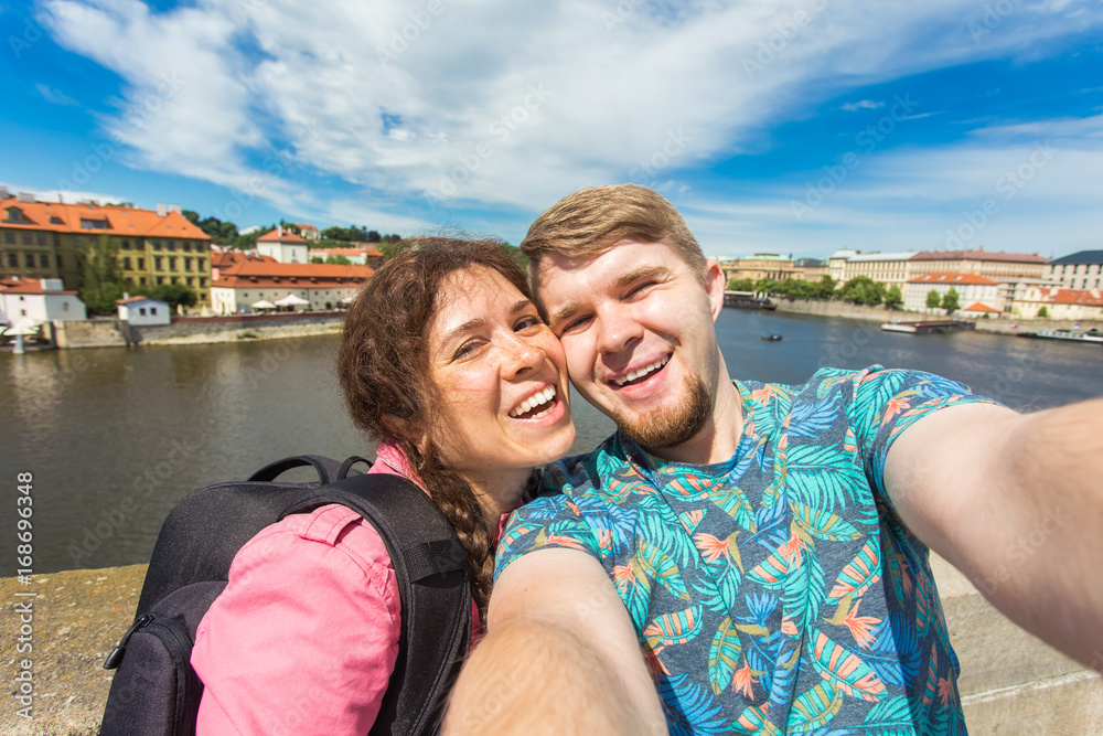 Handsome couple taking selfie with mobile smart phone camera in european city. Vacation, love, travel and holiday concept.