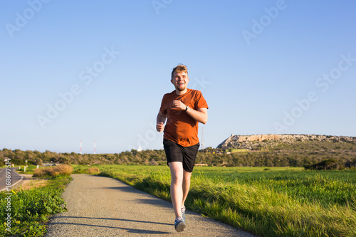 Man running outdoor sprinting for success. Male fitness runner sport athlete in sprint at great speed in beautiful landscape. © satura_