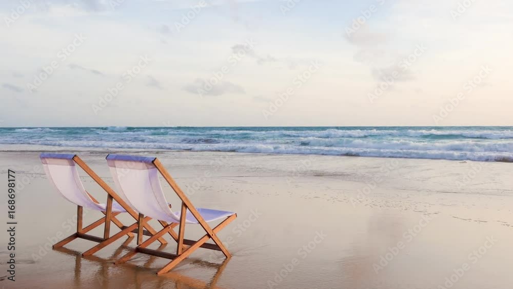 Two beach chairs on the beautiful sunset beach.