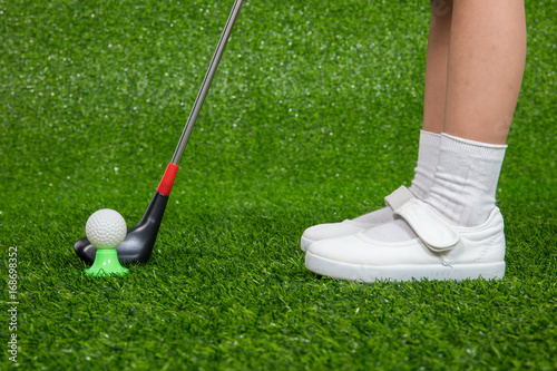 Closeup of a child golfer with putter and ball