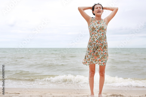Happy Asian young woman stance and relax at the seaside on the vacations.