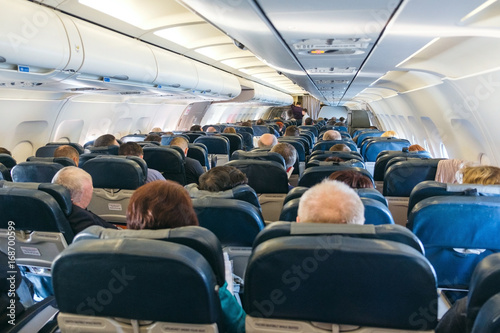 back view of passengers on chairs inside aircraft