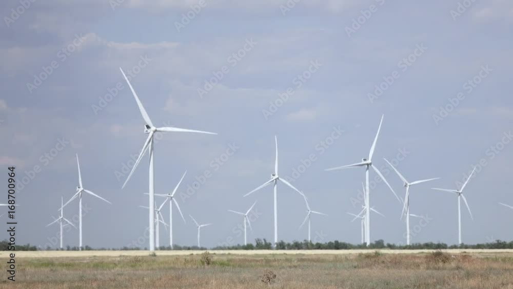 Blades of wind turbines rotate from the wind tree leaves and grass sway Blades of wind turbines rotate from the wind tree leaves and grass sway