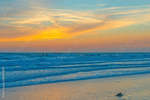 Sea along a sandy beach in the light of sunset in summer