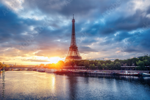 The Eiffel Tower at sunrise. Paris, France. Beautiful skyline of with rising sun and dramatic clouds.