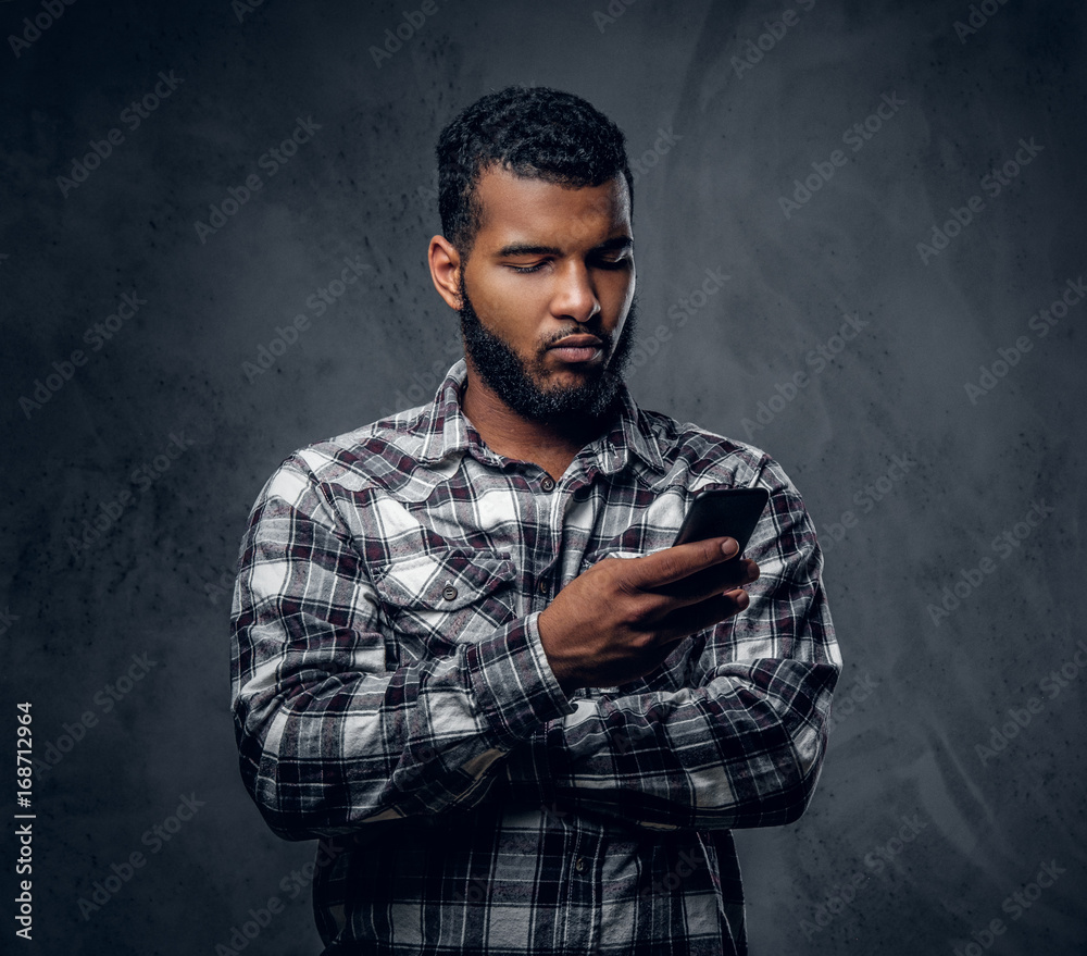Black bearded male dressed in a fleece shirt using a smartphone. Black bearded male dressed in a fleece shirt using a smartphone.