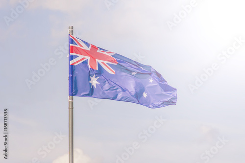 The National flag of Australia flay over the blue sky. Soft toned. © IKvyatkovskaya
