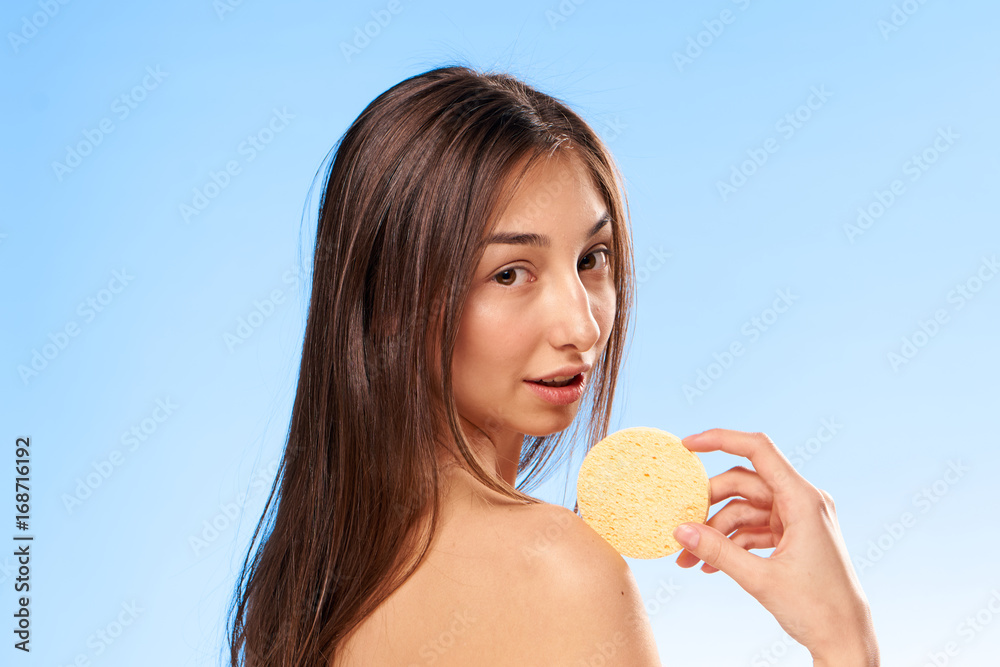 Beautiful young woman on a blue background holds a make-up sponge Beautiful young woman on a blue background holds a make-up sponge