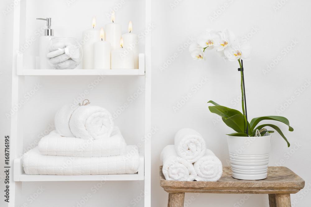 Shelf with clean towels, candles, flowerpot on bathroom wooden table