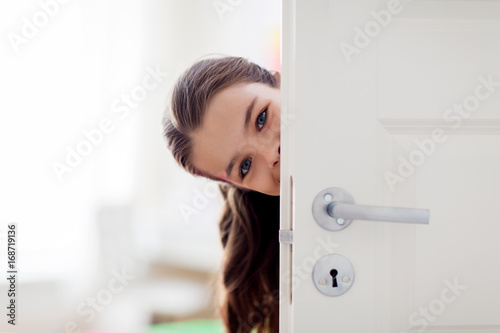 happy smiling beautiful girl behind door at home