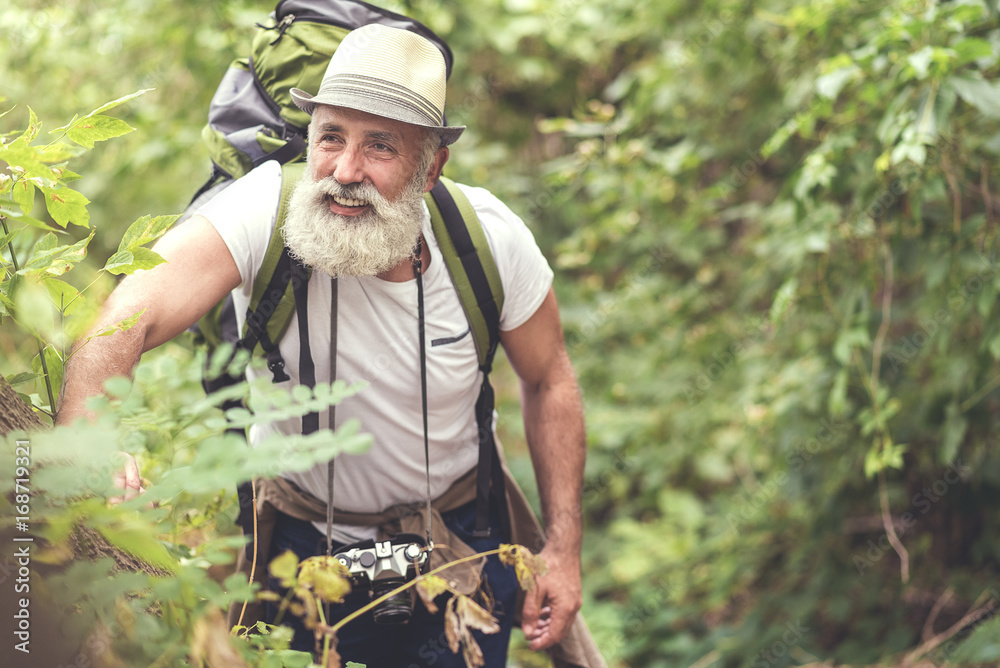 Fototapeta premium Cheerful old man enjoying walk near trees