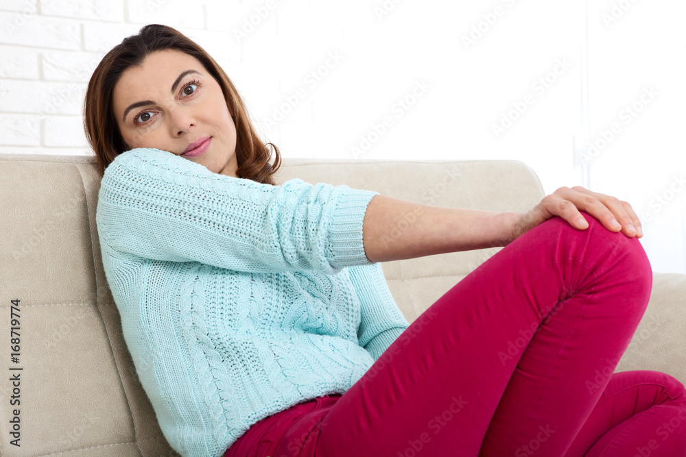 Attractive middle aged woman looking in camera relaxing at home. 