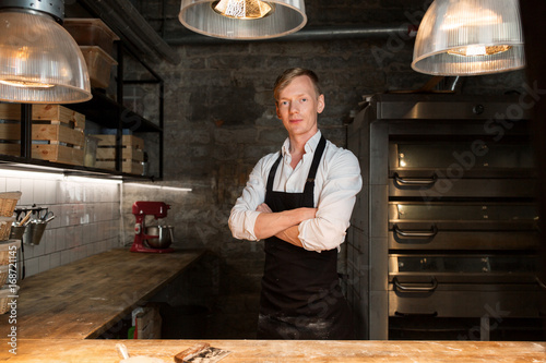фотографія chef or baker in apron at bakery kitchen