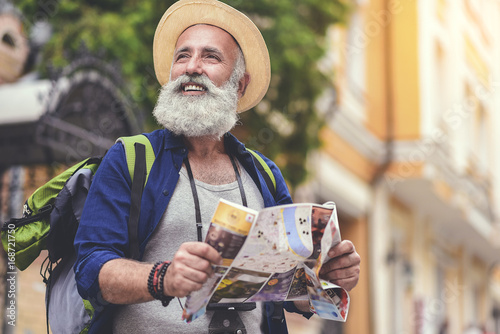 Joyful senior male traveler enjoying walk in town