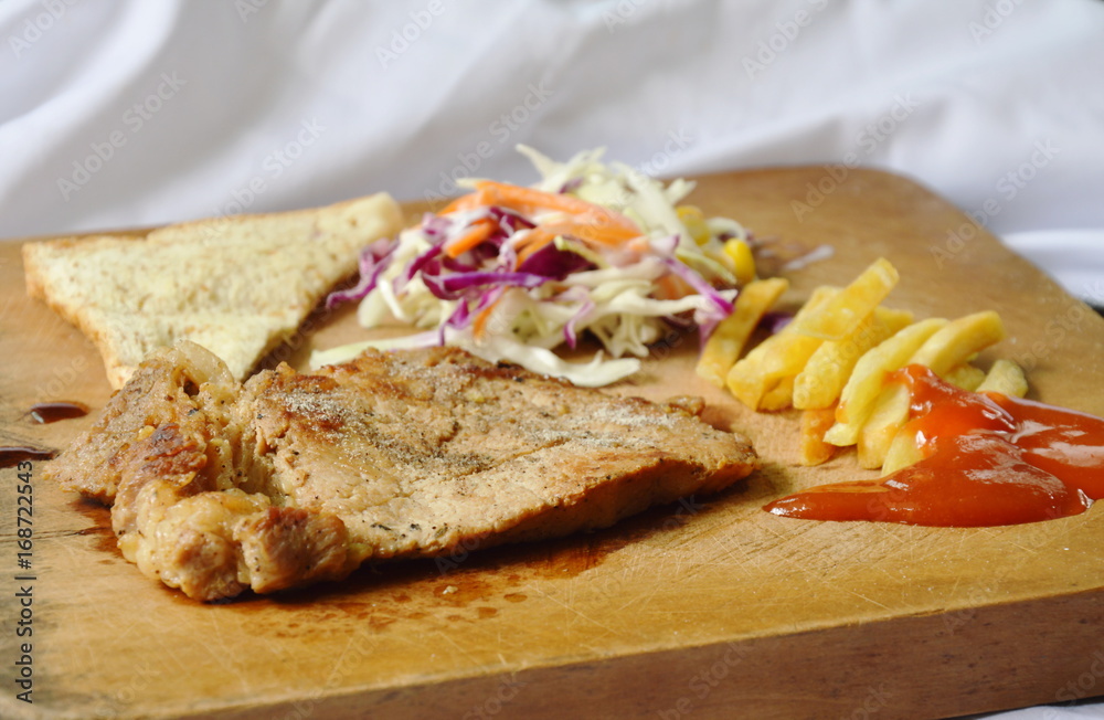 pepper pork steak with French fried and salad on wooden chop block