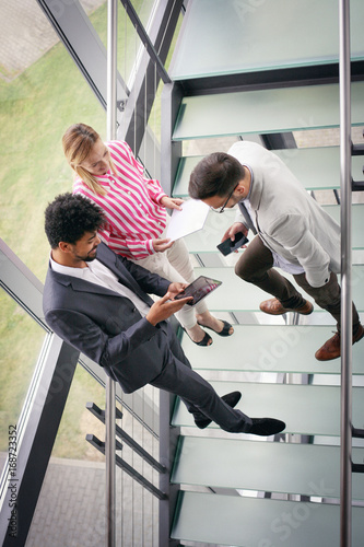 Business people using digital tablet in building office. Business people standing on stairs.