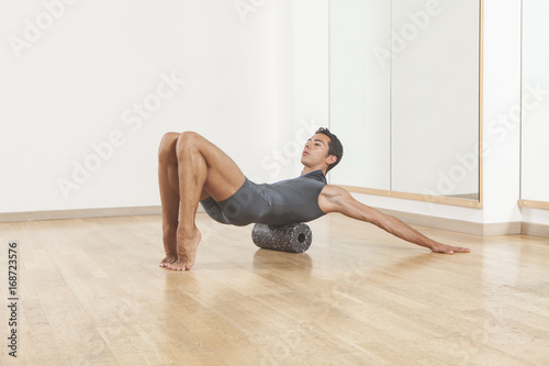professional ballet dancer stretching and warming up using foam roller