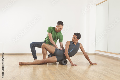 pilates instructor teaching a ballet dancer using foam roller