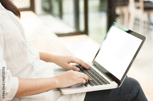 Beautiful woman sitting at the stair and working on a laptop with blank screen