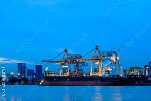 Container loading by crane  cargo ship at shipping port at twilight  Logistics and transportation concept