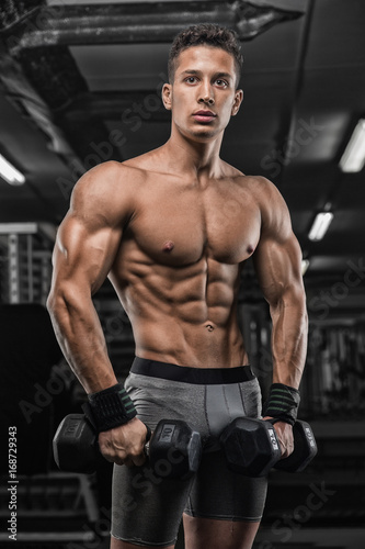 strong and handsome young man doing exercise with dumbbells