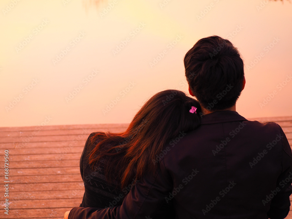 Asian couple see sunset at lake background