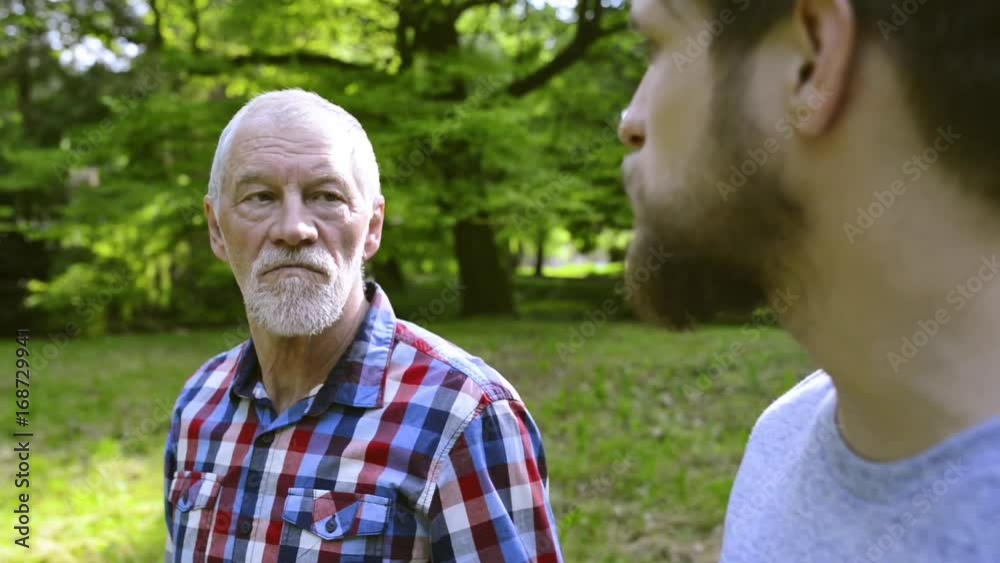 Young man and his senior father on a walk in park. Young man and his senior father on a walk in park.