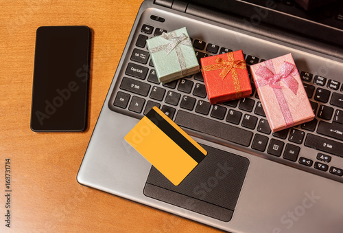 Gift boxes, credit card on laptop keyboard. On-line shopping concept.