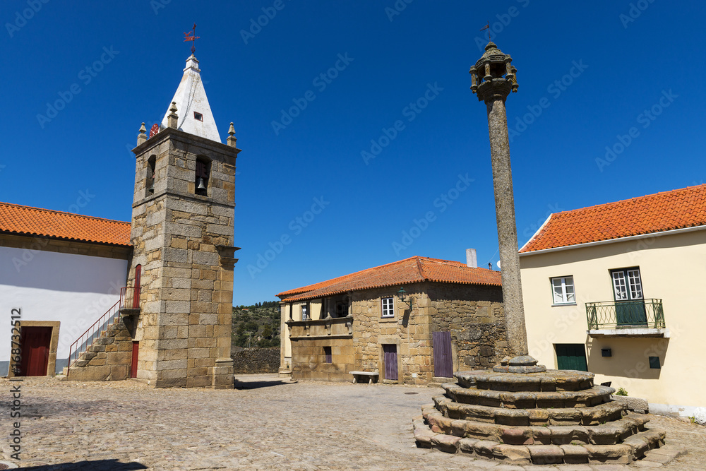 View of the central square of the historic village of Castelo Mendo, in Portugal, with a church and pillory; Concept for travel in Portugal