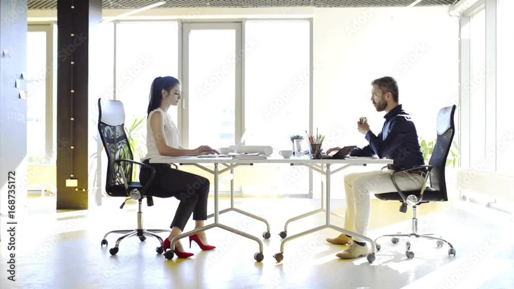 Two business people in the office working together. Two business people in the office working together.