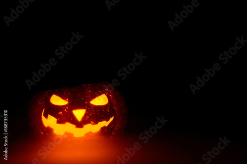 Composed glowing carved pumpkin lying on surface in mist