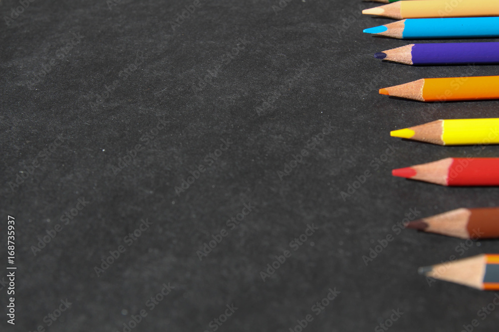 Queue of colorful pencils on the black ground Queue of colorful pencils on the black ground