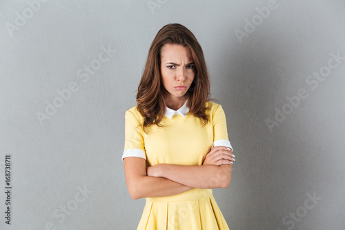 Upset girl standing with arms folded and looking at camera