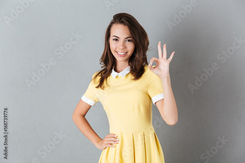 Attractive smiling girl in dress showing ok gesture