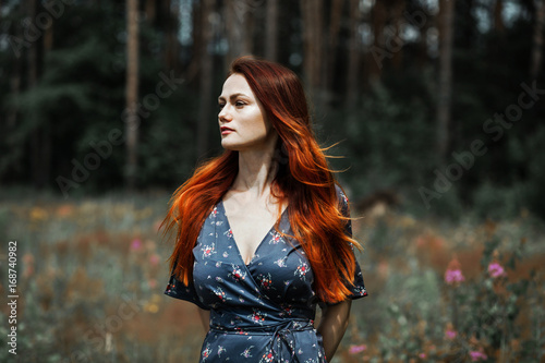 Portrait of a beautiful red-haired girl in a flower field