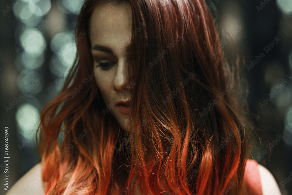 Portrait of a beautiful red-haired girl on a background of nature