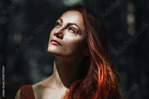 Portrait of a beautiful red-haired girl on a background of nature